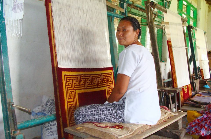 A weaver at the Choephelling Tibetan settlement near Miao working on a handwoven carpet