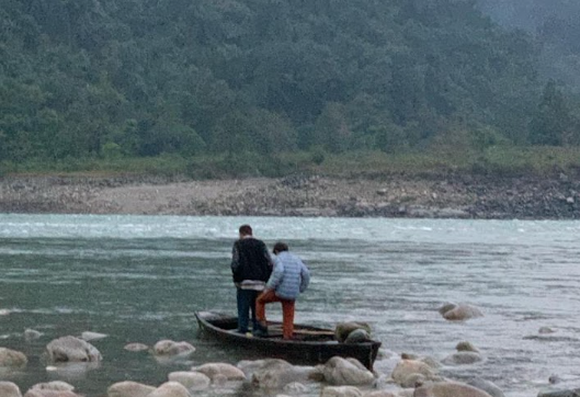 A wooden boat crossing a wide river inside Namdapha National Park