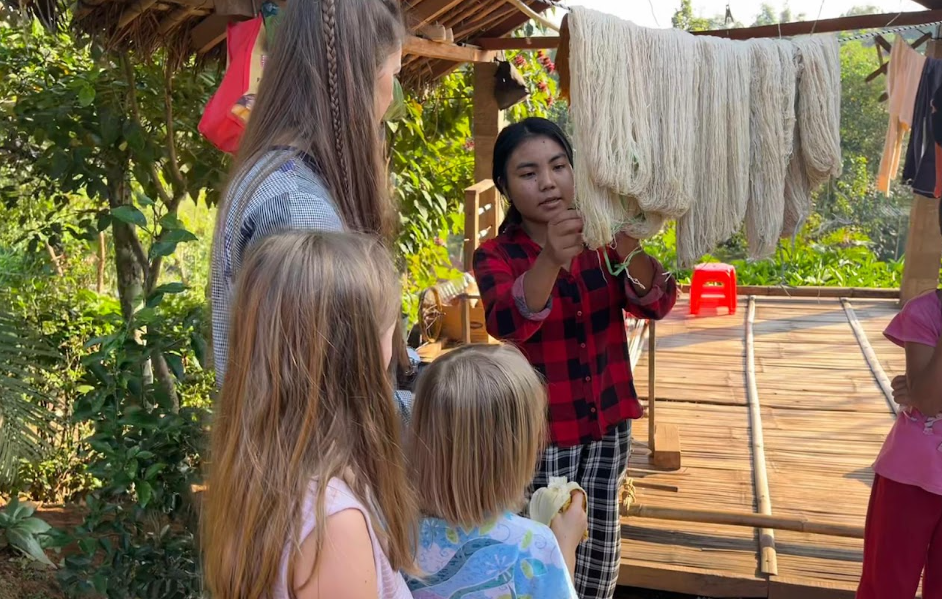 Weaver showing handspun Eri silk thread to visiting children