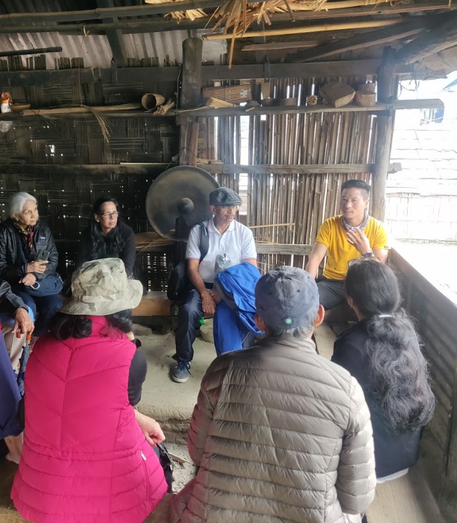 Group sitting inside a wooden community hall listening to a talk