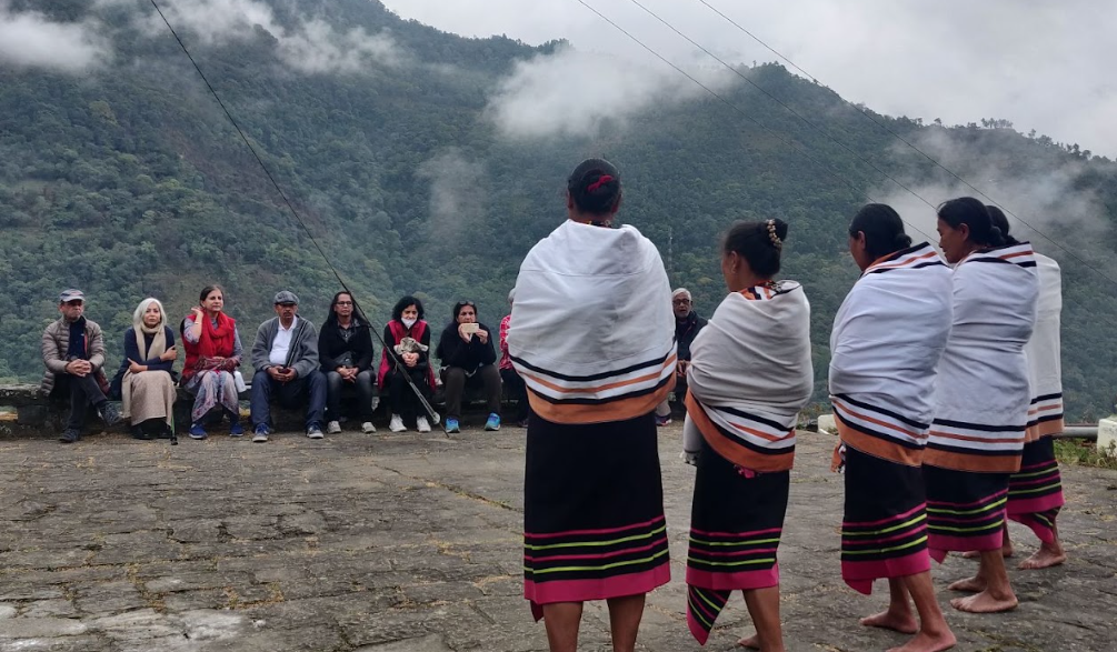 Women in traditional Angami shawls performing a lullaby before a seated audience