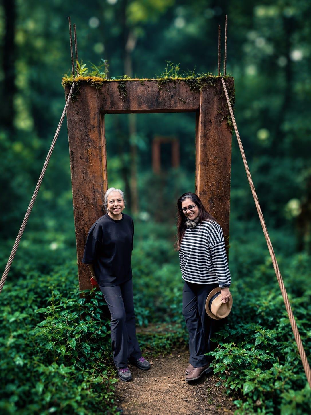 Two women standing in a wooden frame on a forest footbridge