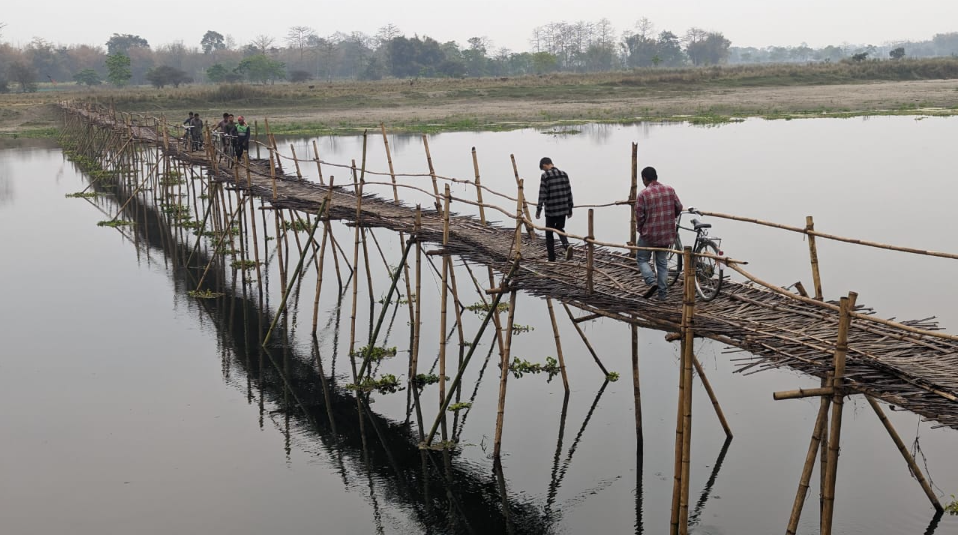 People crossing a bamboo bridge over a river on Majuli