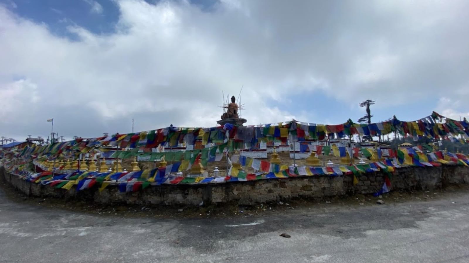 A long wall of prayer flags beneath an overcast sky near a stupa