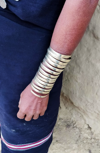 Close-up of a forearm wearing a stack of silver bangles against a dark blue skirt